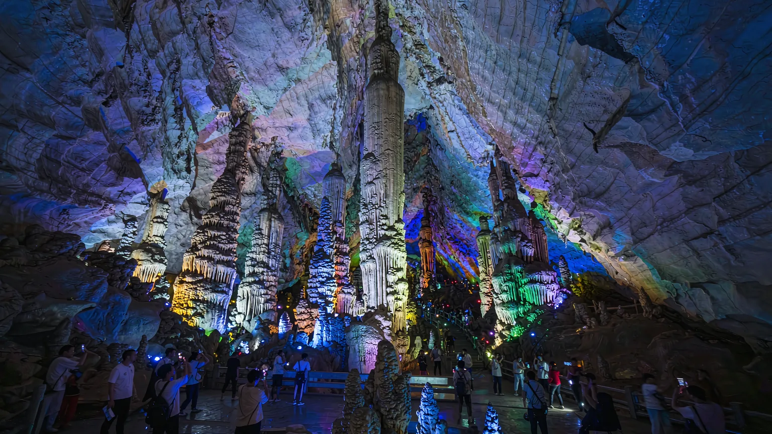Main chamber of Reed Flute Cave with massive colorful limestone formations resembling a palace