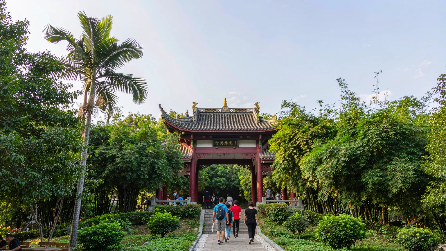 Entrance pathway to Reed Flute Cave with lush greenery and a traditional gate
