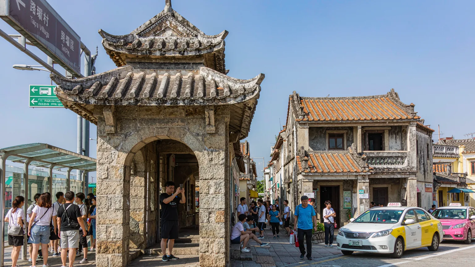 Entrance to Rua do Cunha with archway and tourists in Taipa Village, Macau
