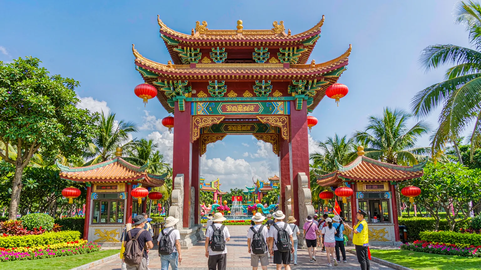 Tourists entering Sanya Romance Park through ornate gate with red lanterns