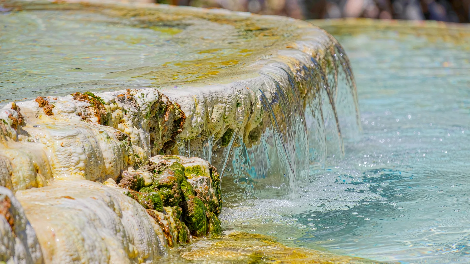 Close-up of travertine rim and clear water flowing over mineral deposits at Shenxianchi