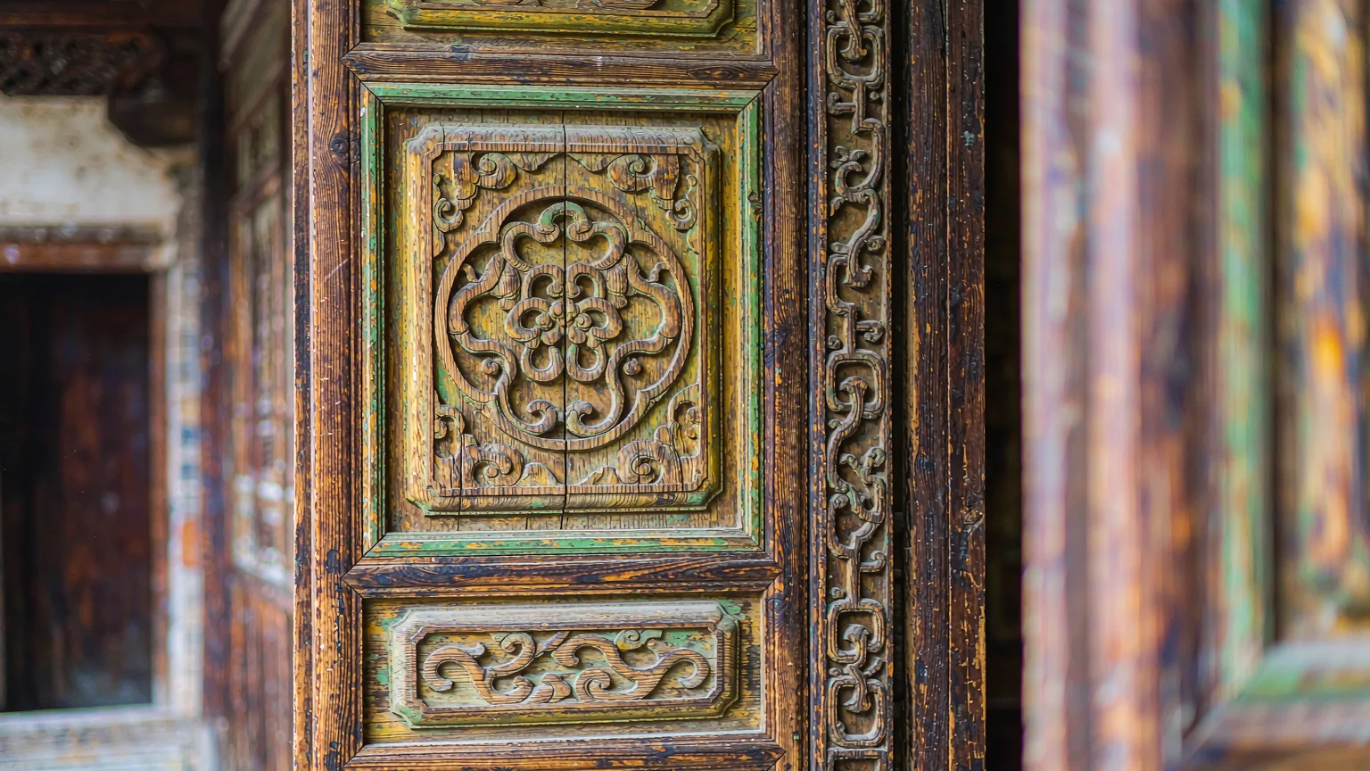 Close-up of intricate wooden carvings on a traditional Bai door in Shuanglang Ancient Town