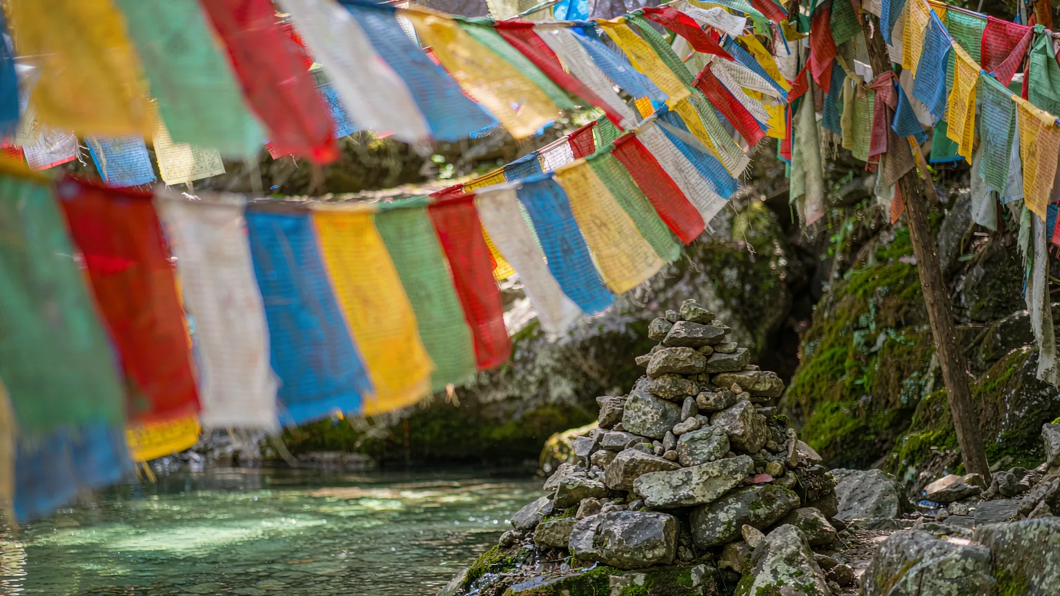 Colorful prayer flags at a shrine in Shuimogou with spring water