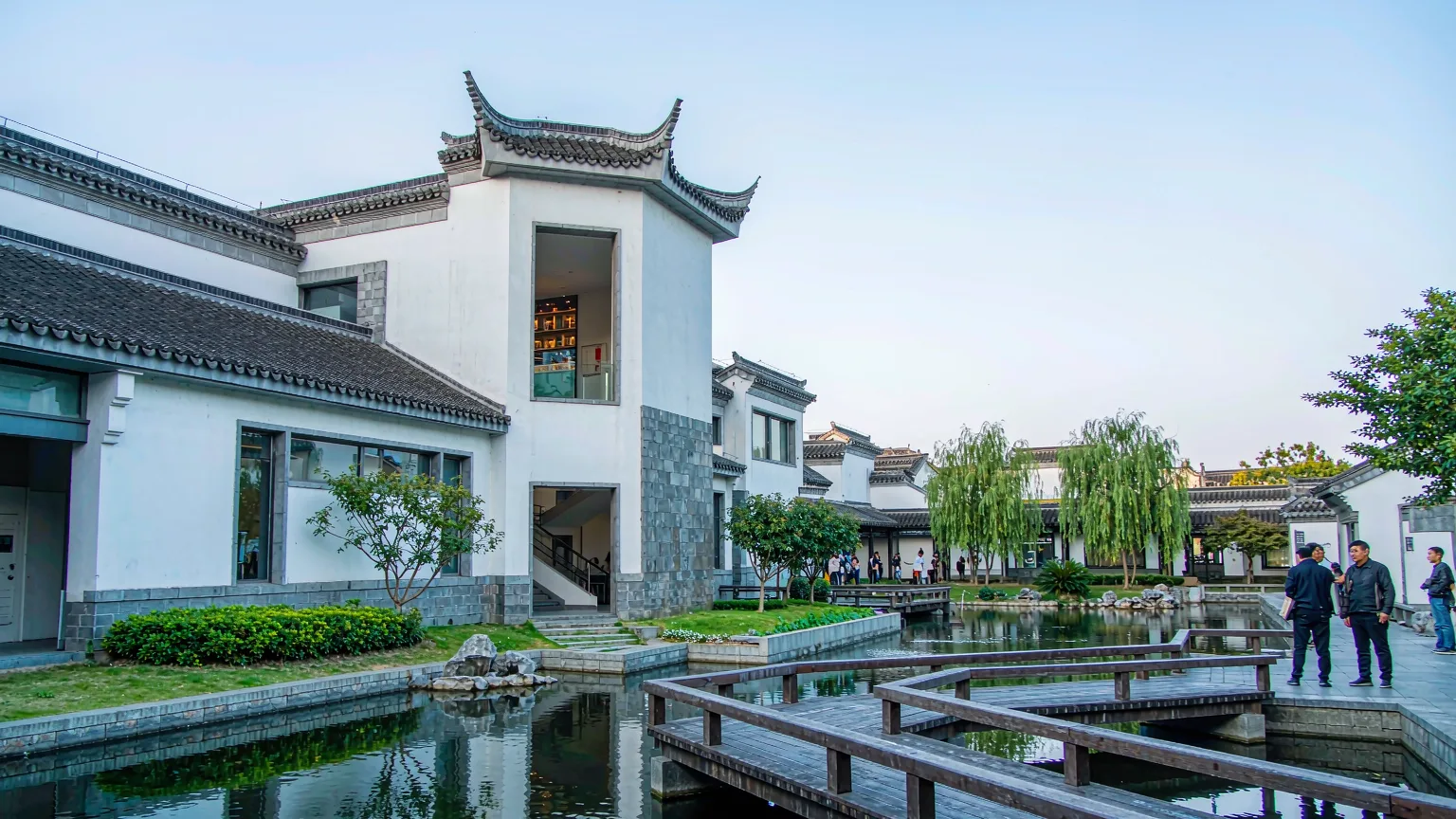 Modern Suzhou Museum architecture with white walls, grey tiles, and a water courtyard.