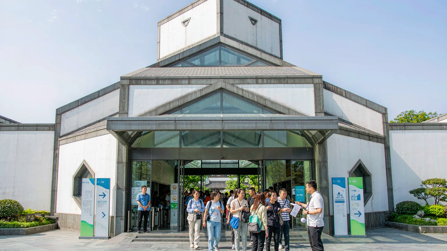 Tourists entering Suzhou Museum with a guide through the modern entrance.