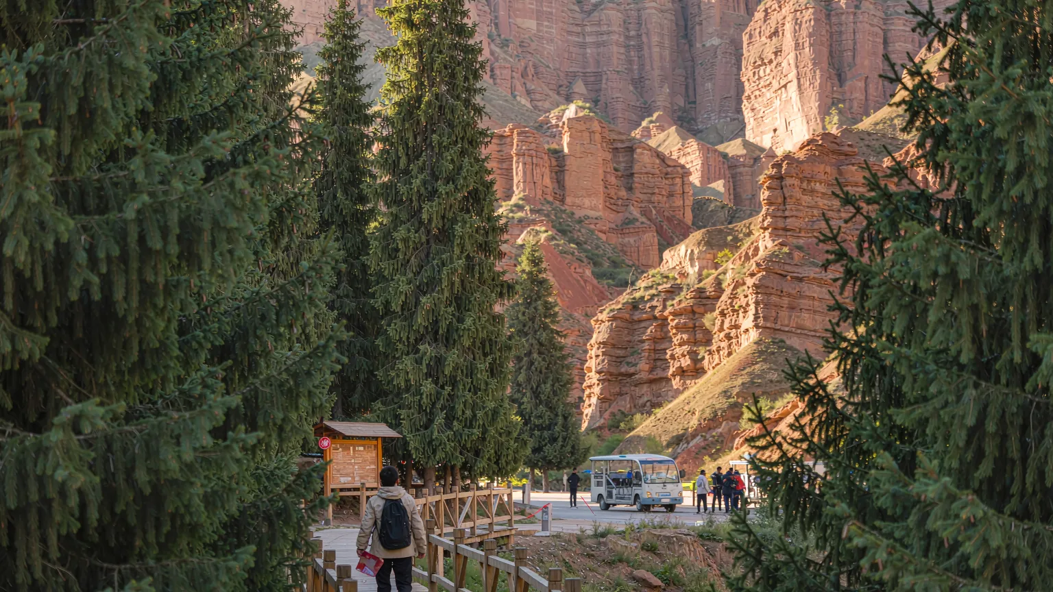 Visitor on boardwalk entering Tianshan Grand Canyon with shuttle bus behind