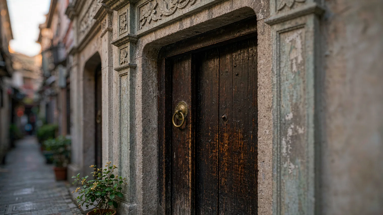 Close-up of a carved shikumen stone gate with brass knocker in Tianzifang