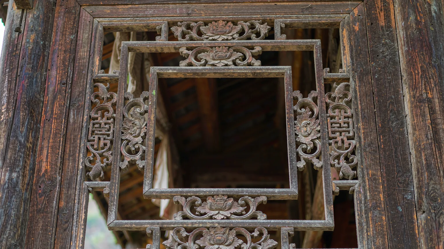 Close-up of intricate wooden carvings on Tujia window frame