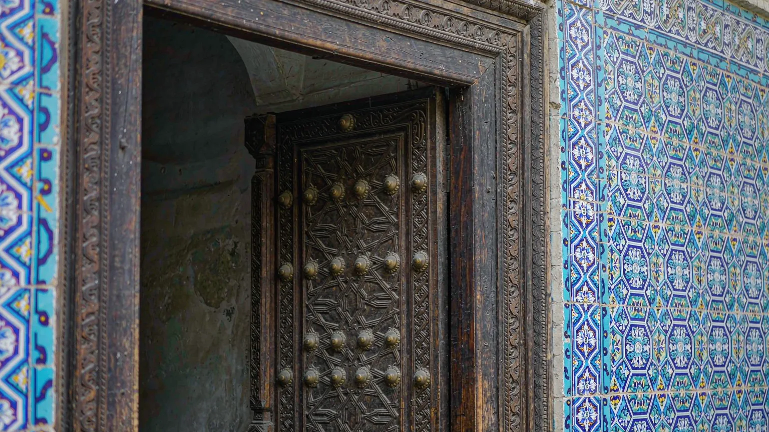 Close-up of ornate carved door and blue tiles at Urumqi Grand Bazaar
