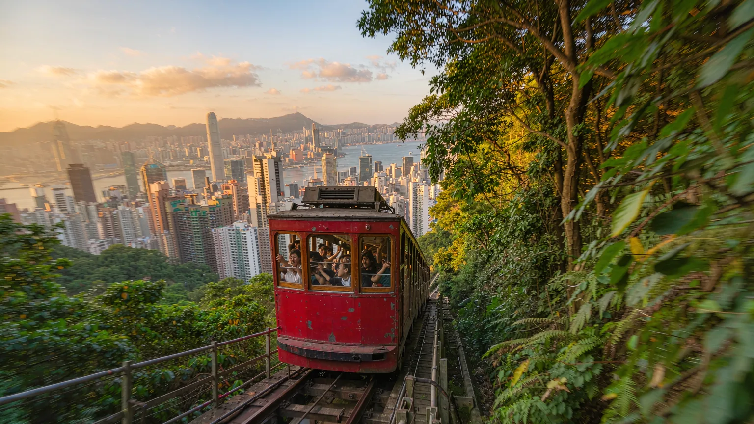 Historic Peak Tram climbing through lush greenery with city views