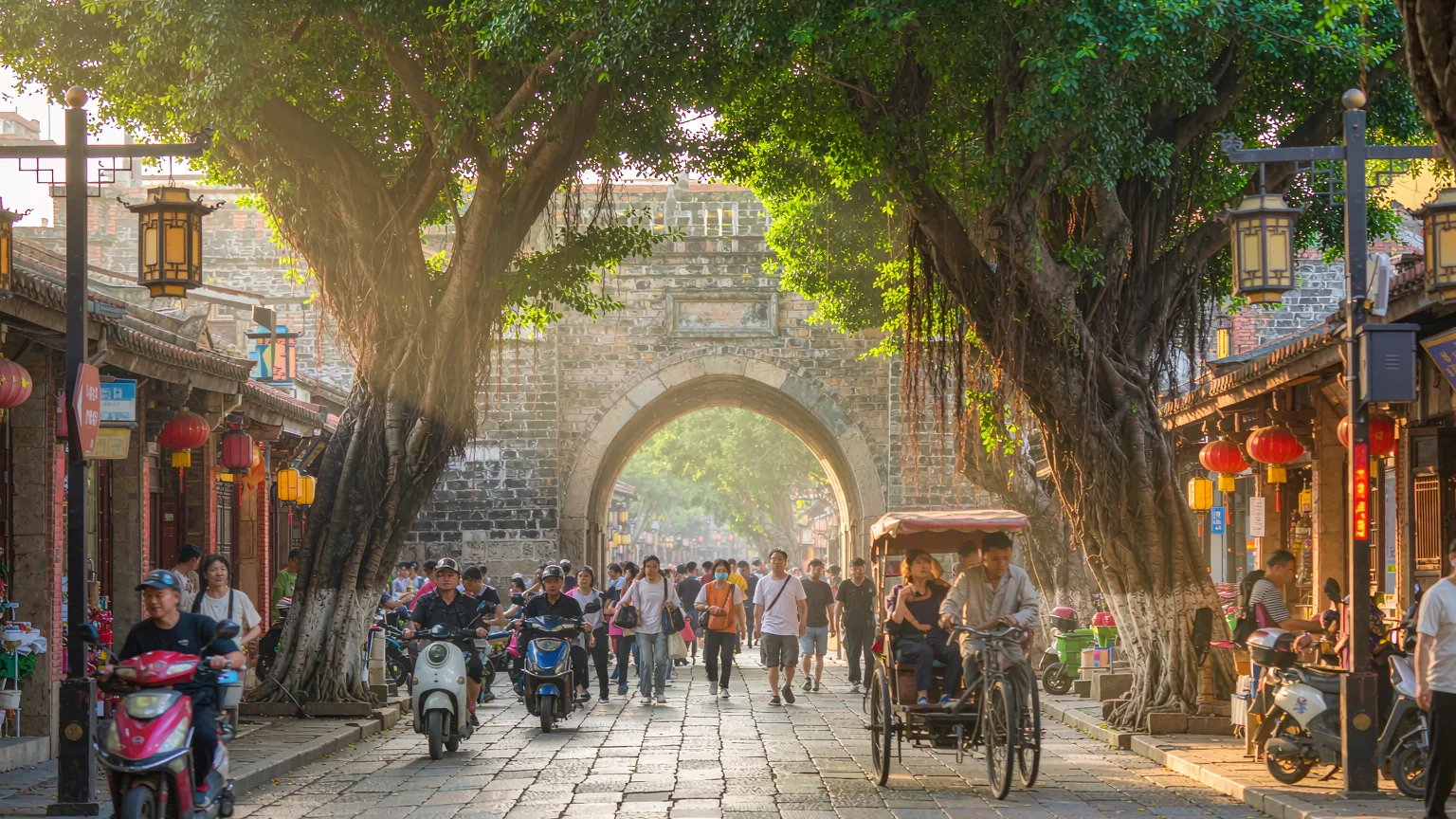 Travelers entering West Street Quanzhou beneath banyan trees and lanterns