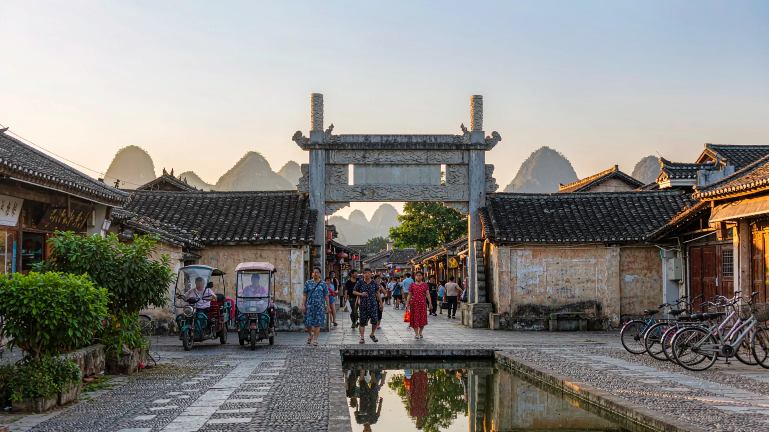 Entrance archway to West Street Yangshuo with tourists and rickshaws