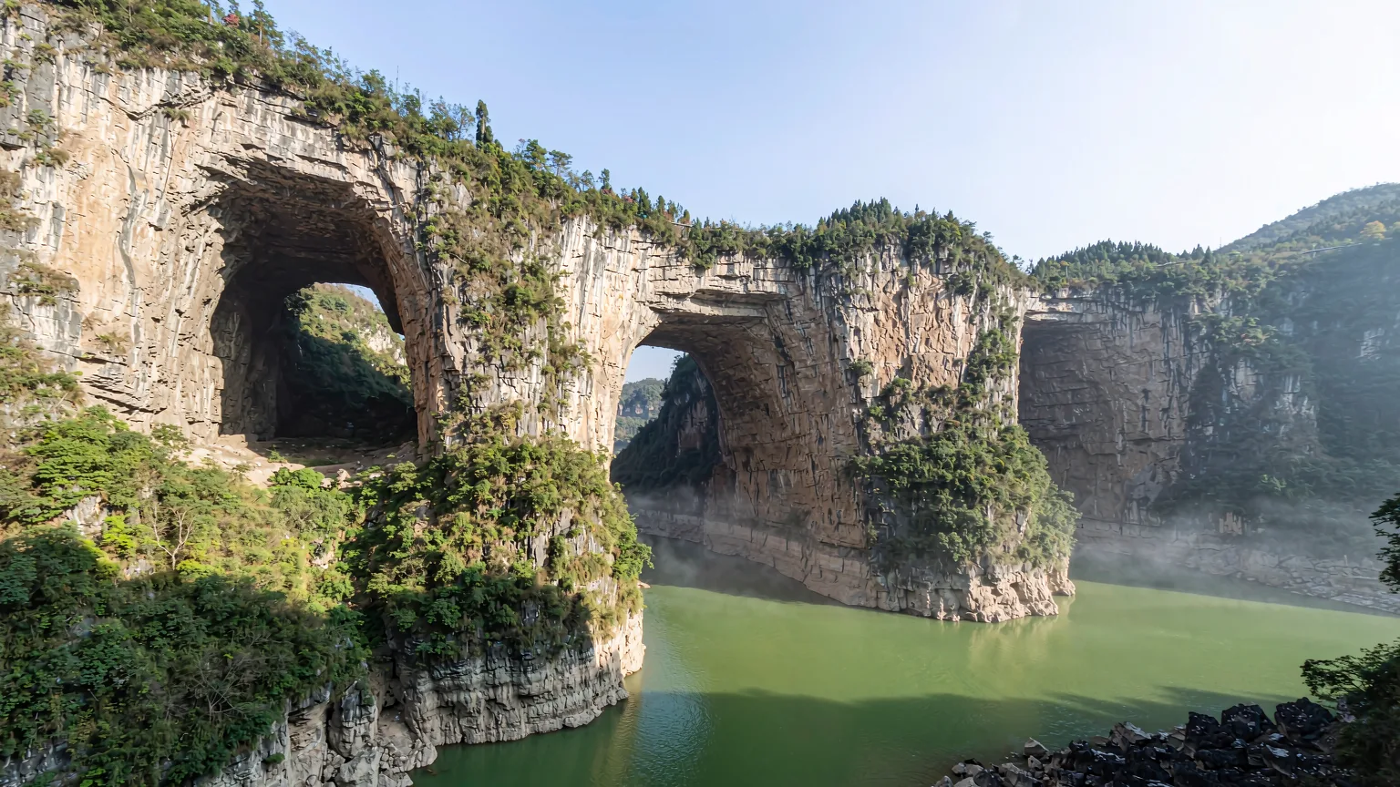 Three colossal limestone arches spanning deep gorges at Wulong