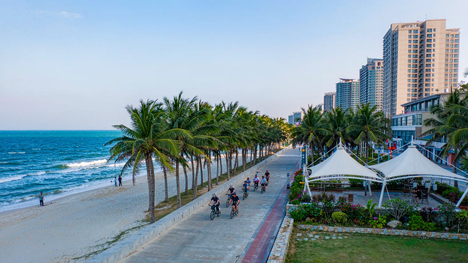 Cyclists on palm-lined boardwalk along Xiamen Island Ring Road