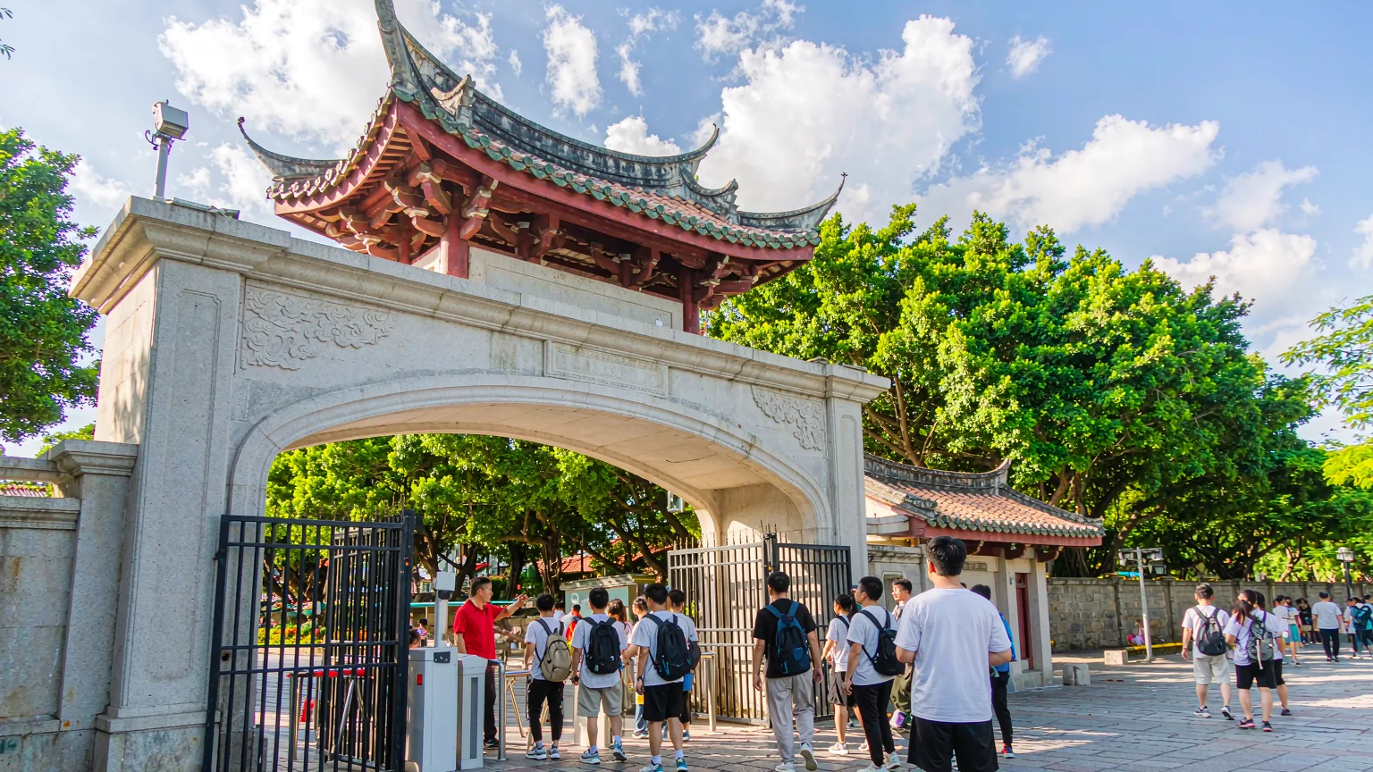 Visitors entering Xiamen University through main gate with guide