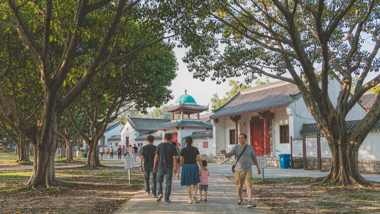 Tree-lined pathway leading to Xiangfei Garden entrance with dome in view