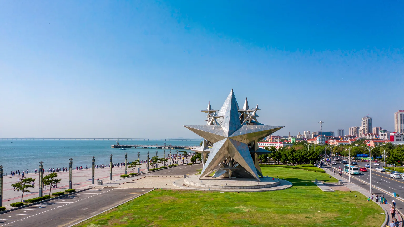 Central star monument at Xinghai Square with lawns and sea