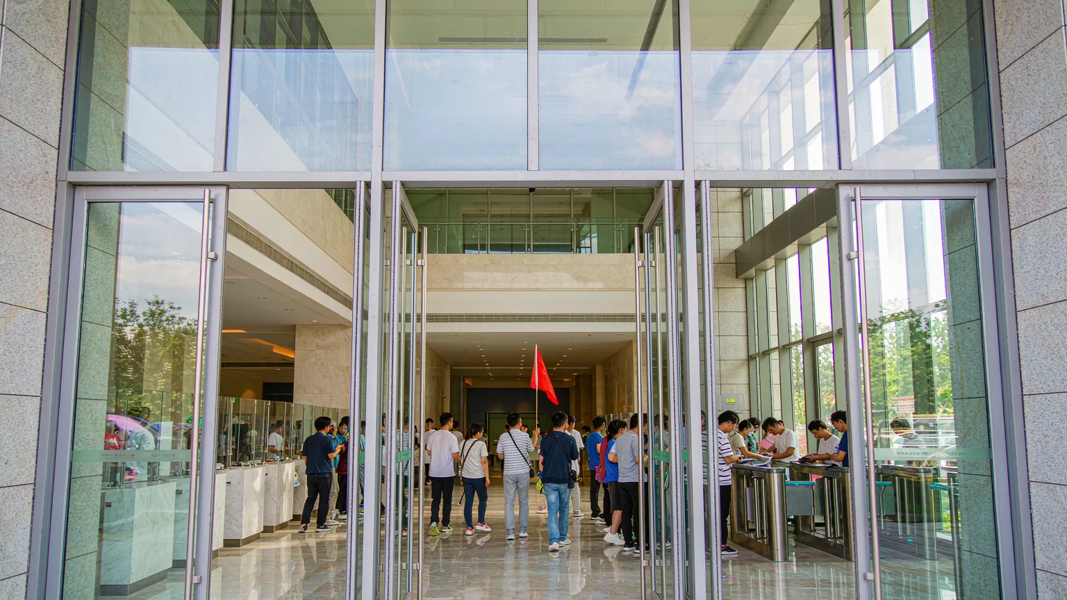 Tourists entering Xinjiang Museum lobby with guide and ticket area