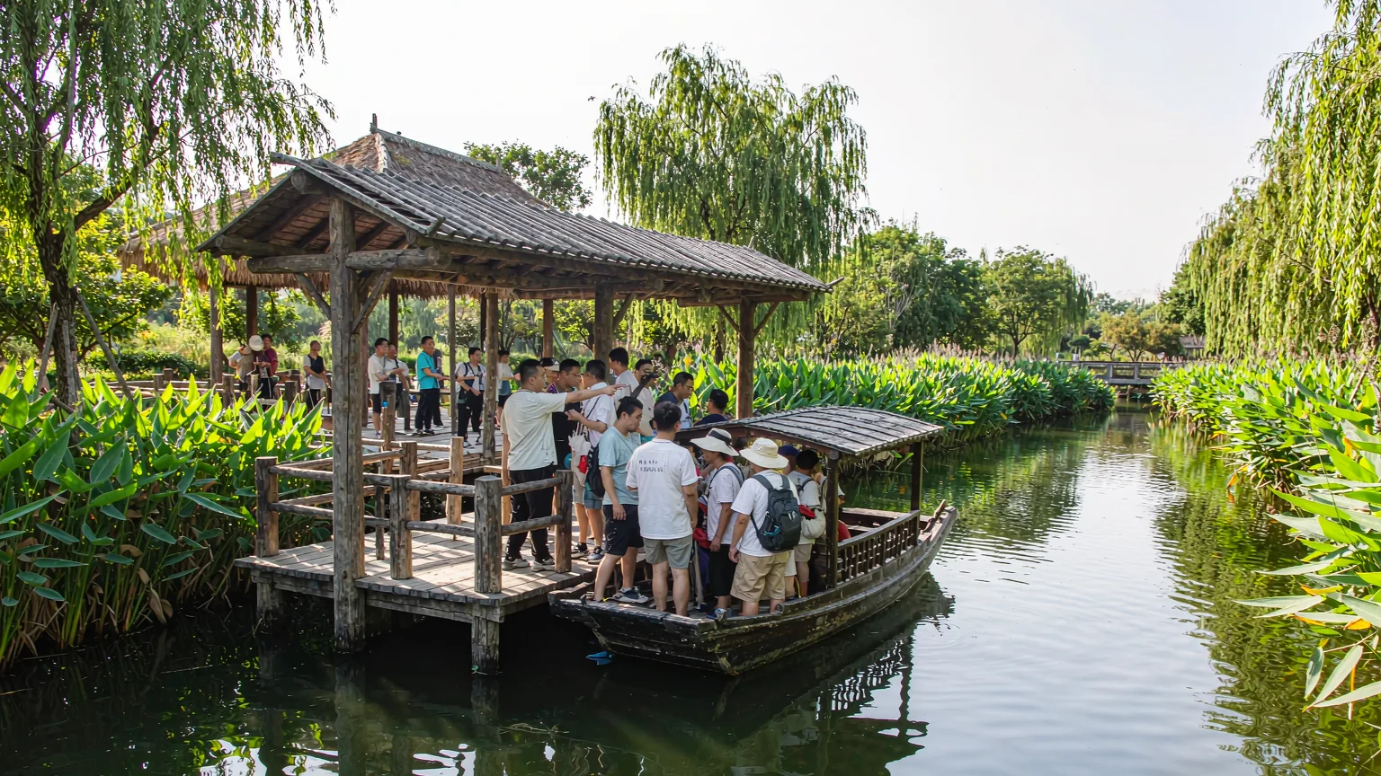 Tourists boarding a wooden boat at a rustic dock in Xixi Wetland