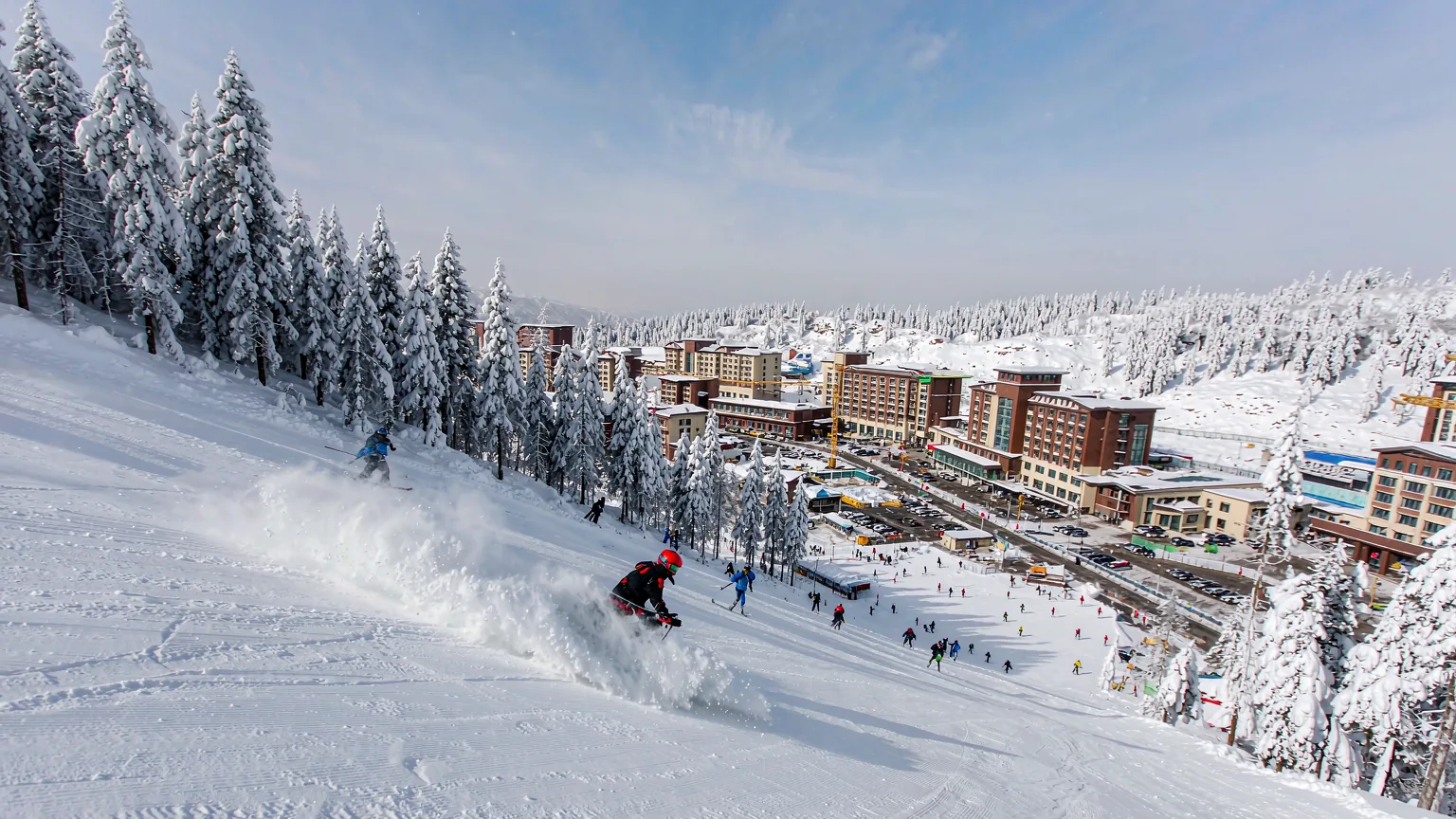Skiers descending a groomed run at Yabuli Ski Resort with lodge below