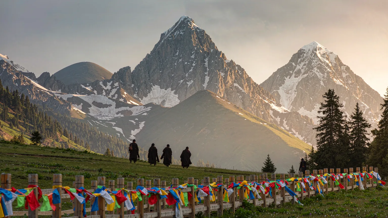 Tibetan pilgrims on kora path with prayer flags and snow peaks