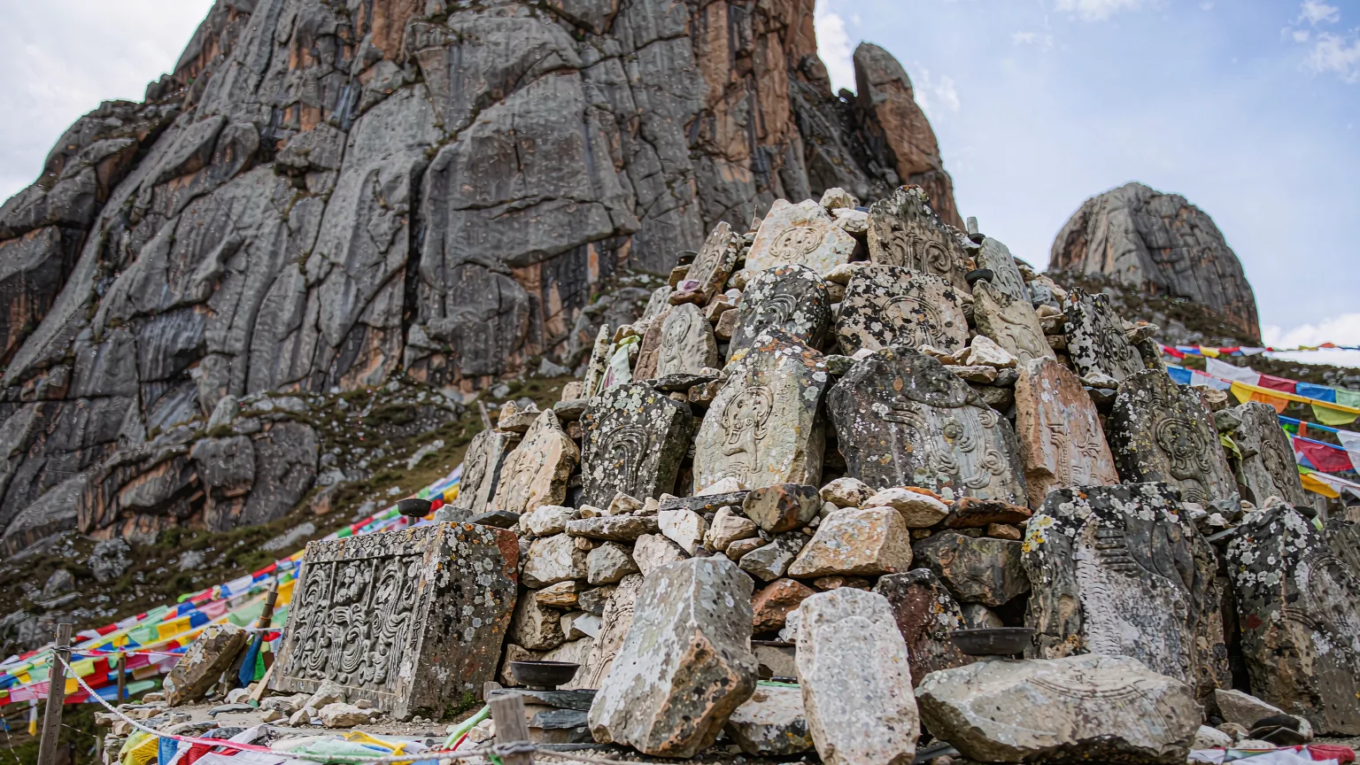 Close-up of Tibetan mani stones and prayer flags at Yading