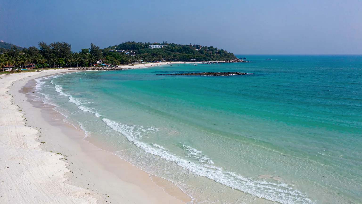 Yalong Bay's white sand beach, calm turquoise sea and green hills