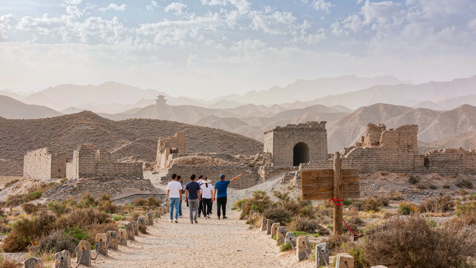 Tourists walking toward Yangguan Pass entrance on sandy path