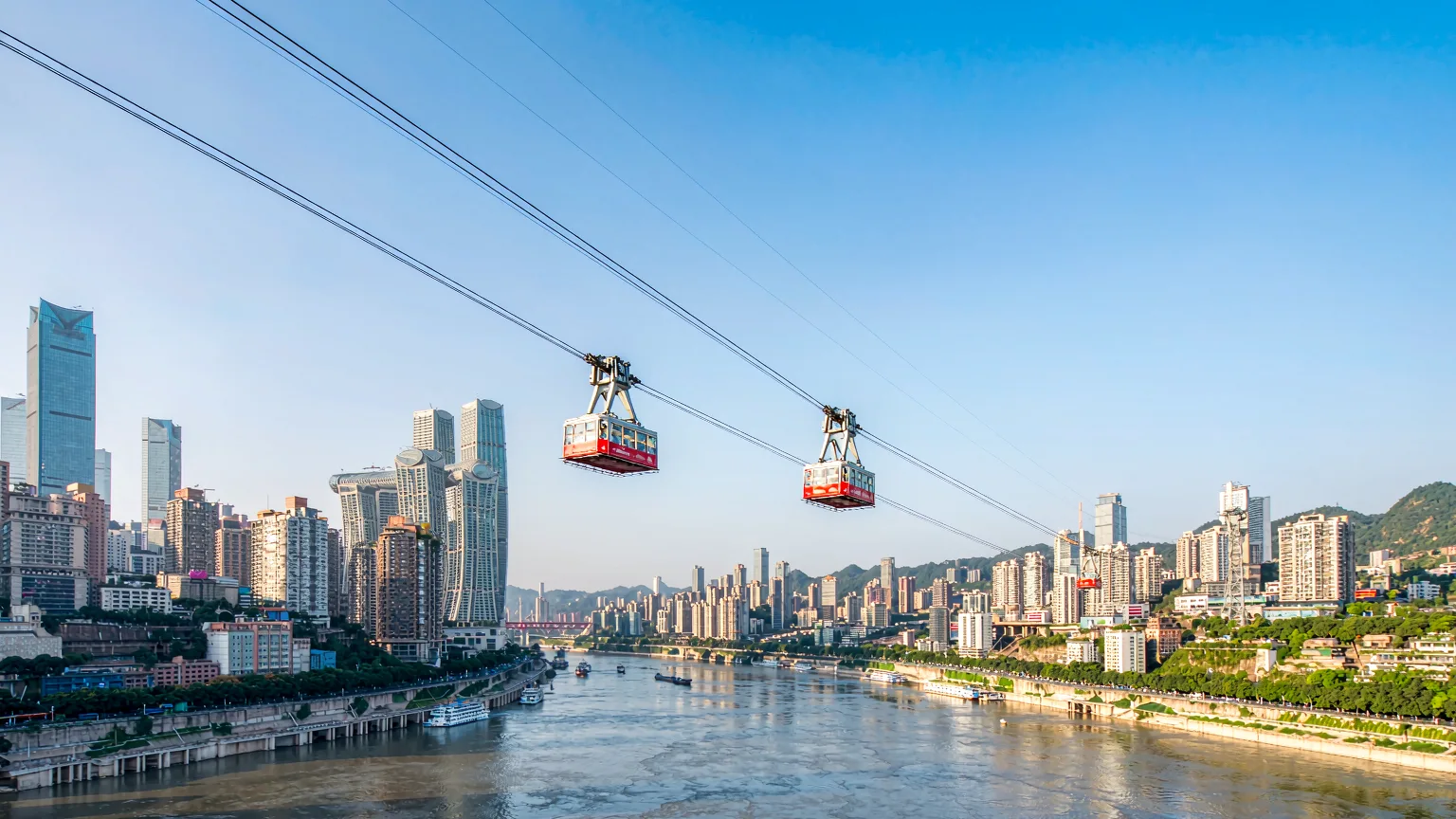 Yangtze River Cableway cabins crossing river with cityscape and hills in background