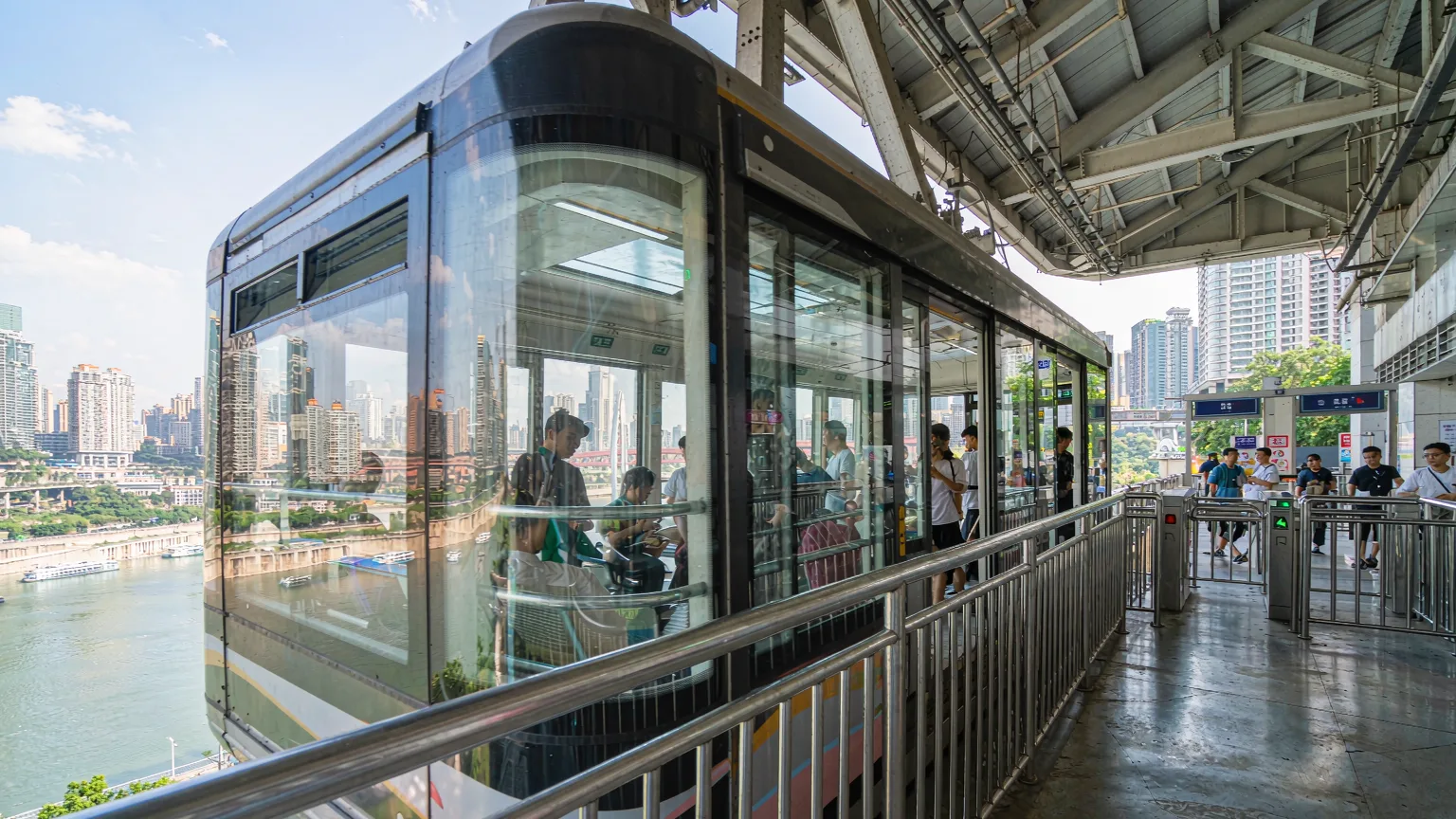 Passengers boarding Yangtze River Cableway at station platform with city view