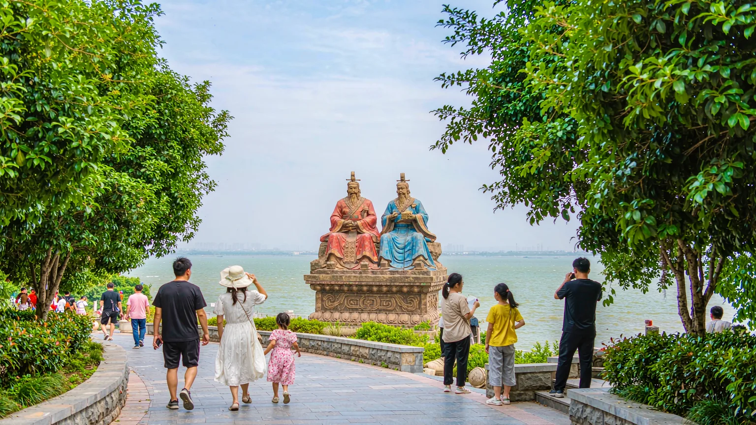 Tourists walking on a stone path toward the Yanhuang statues