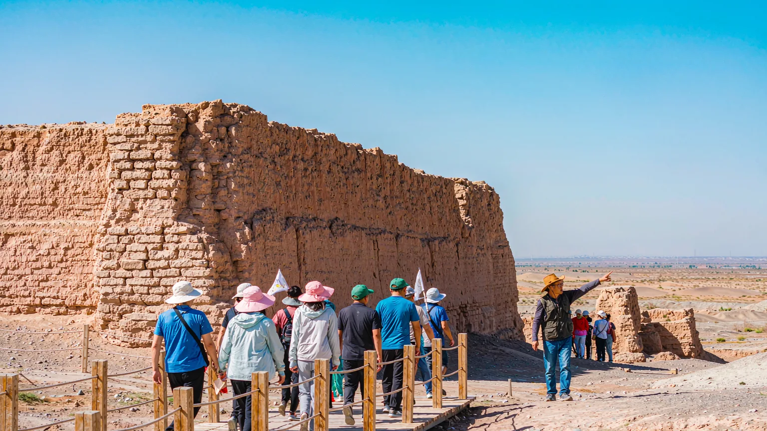 Tourists on boardwalk approaching Yumen Pass ruins in desert