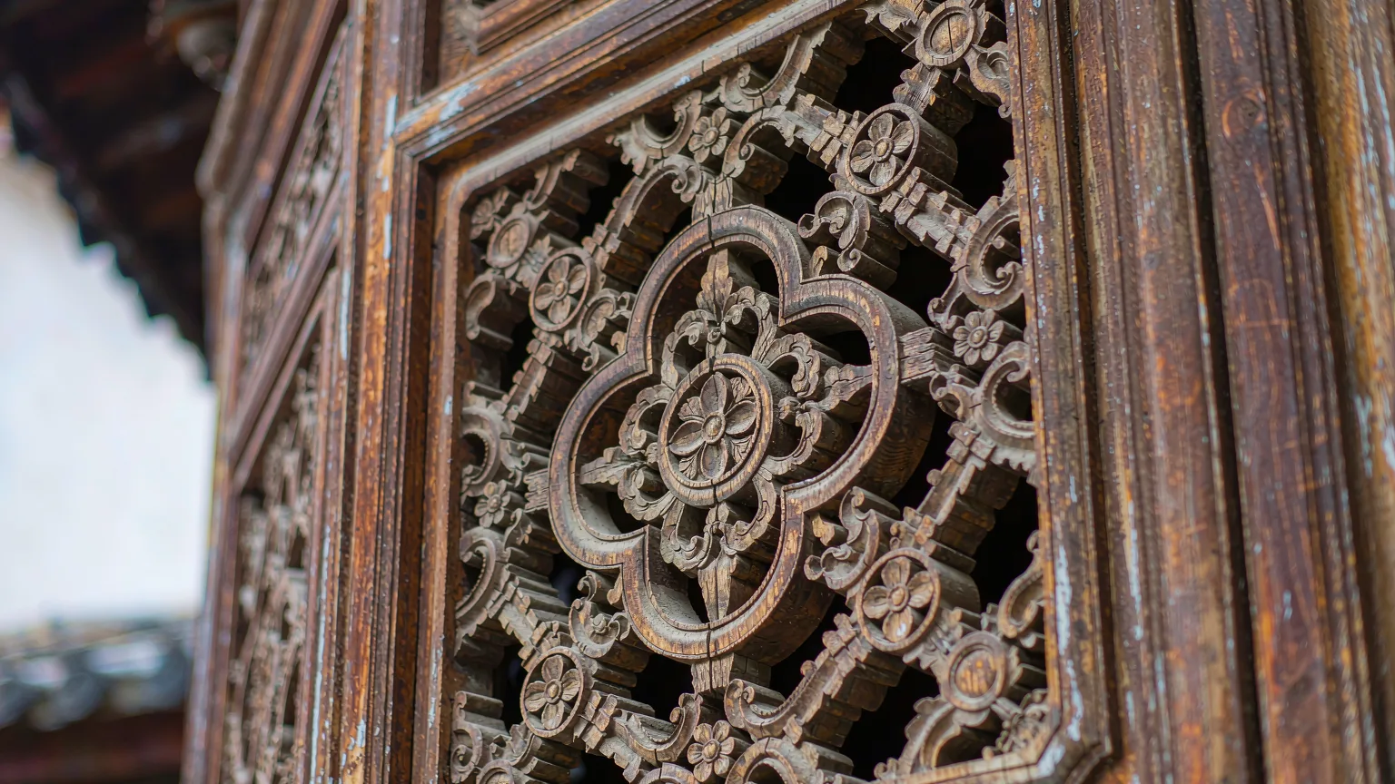 Close-up of intricate Bai-style woodcarving on a door panel.