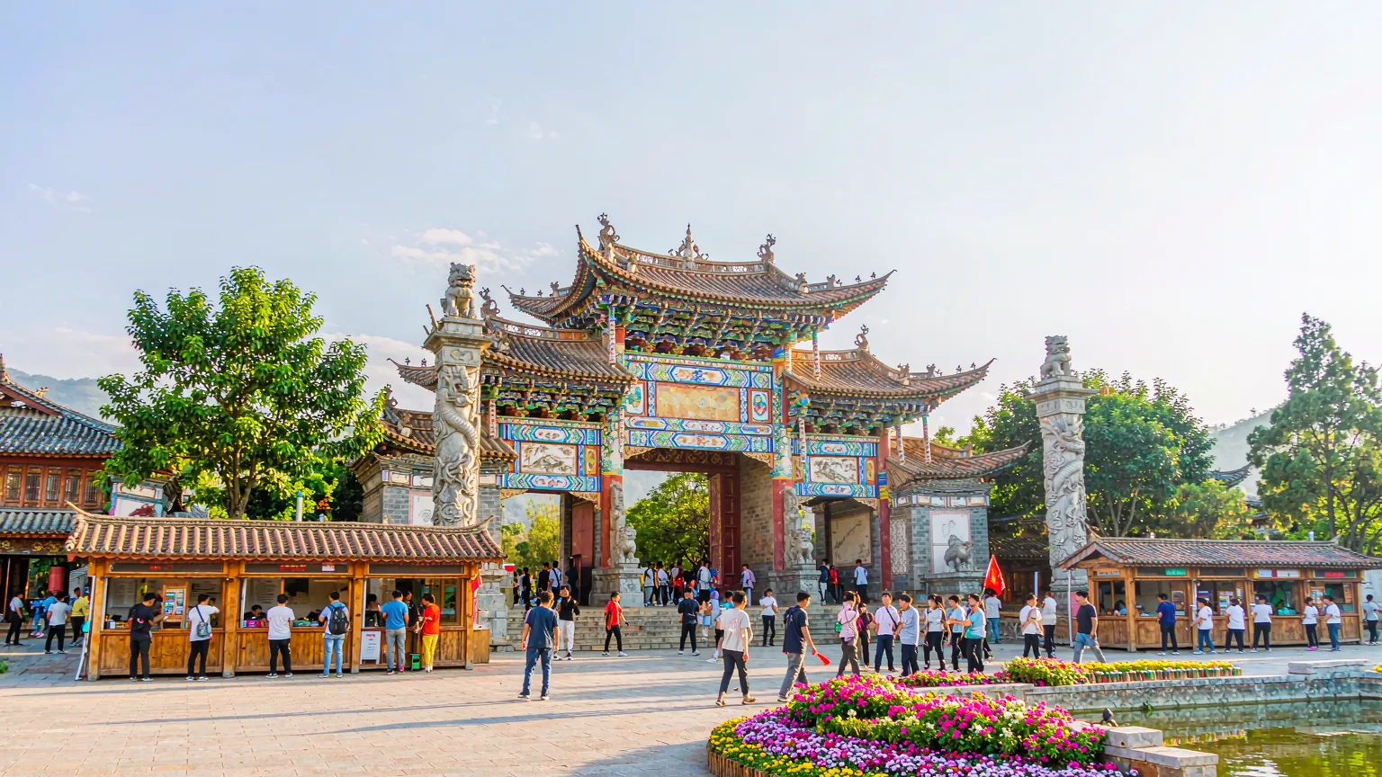 Main entrance gate of Yunnan Nationalities Village with visitors and guide.