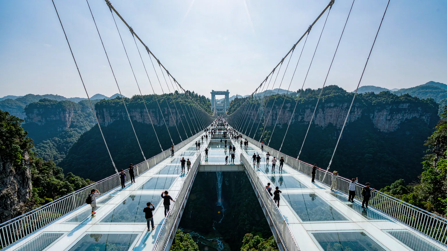 Glass-bottomed deck of Zhangjiajie Grand Canyon Bridge with visitors above a deep gorge