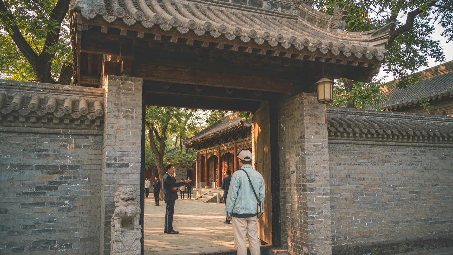 Visitor entering Zhenguo Temple courtyard with guide on a stone path