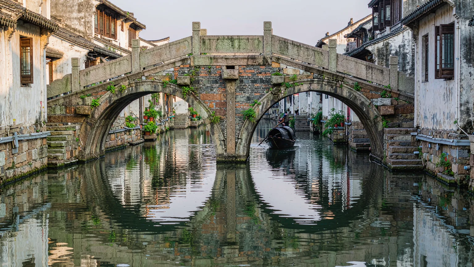Detailed view of Zhouzhuang's Twin Bridges with reflections and boat